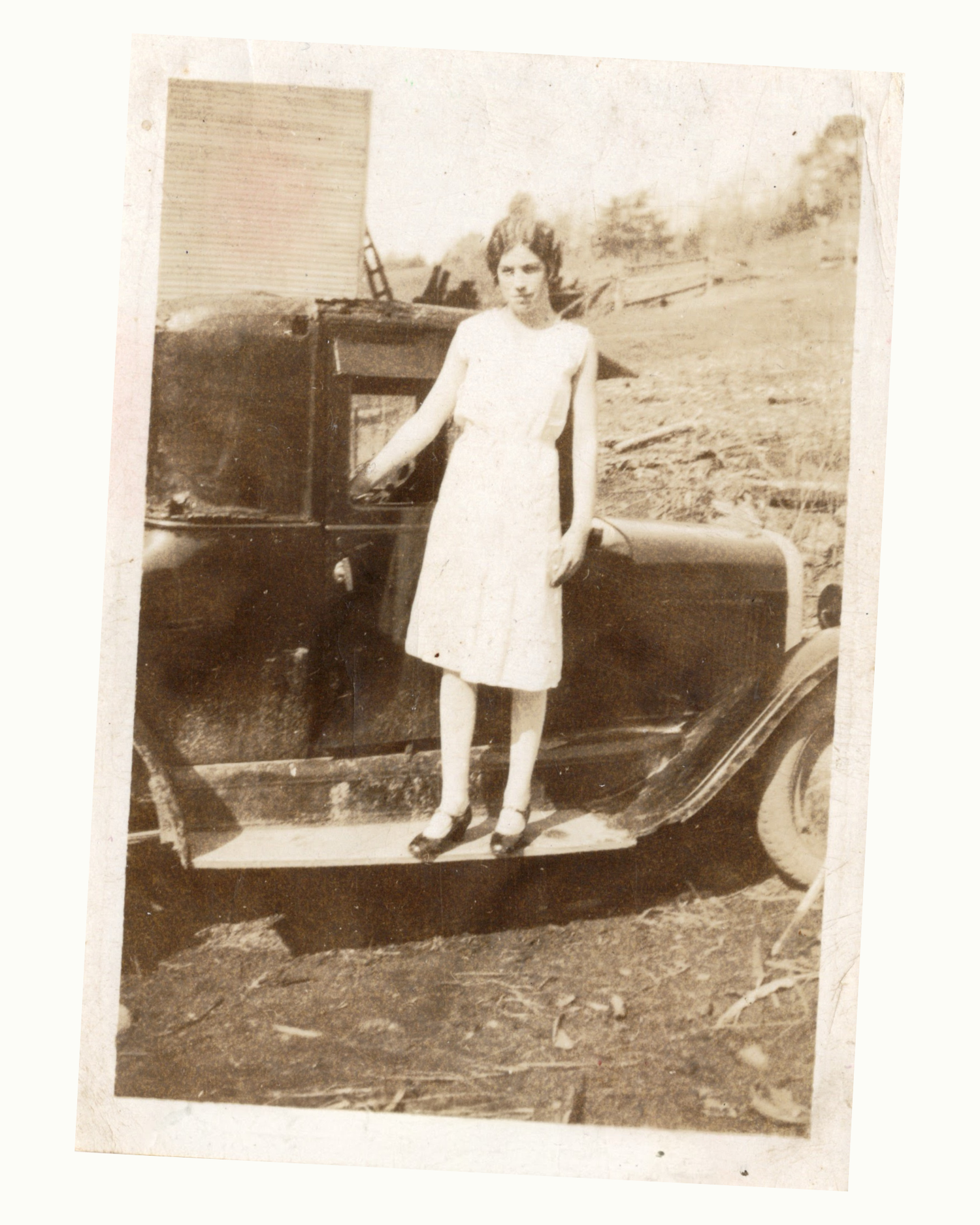 Vintage black and white photo of a woman standing next to an old car